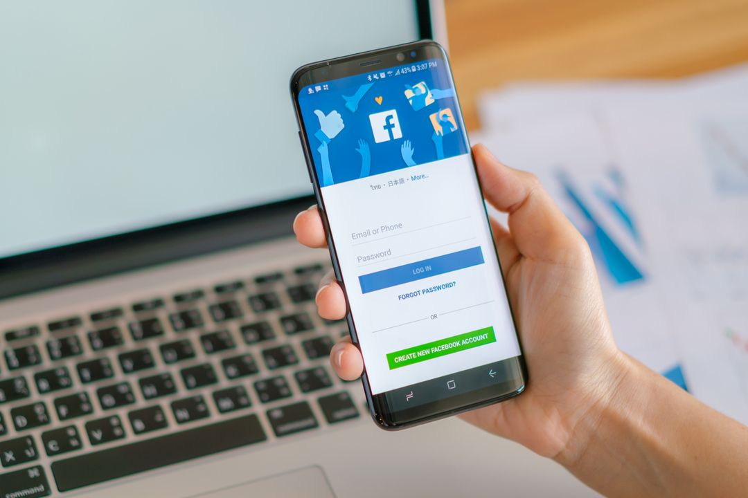 Pessoa segurando celular com a página de login do Facebook aberta para configuração do Facebook Ads.